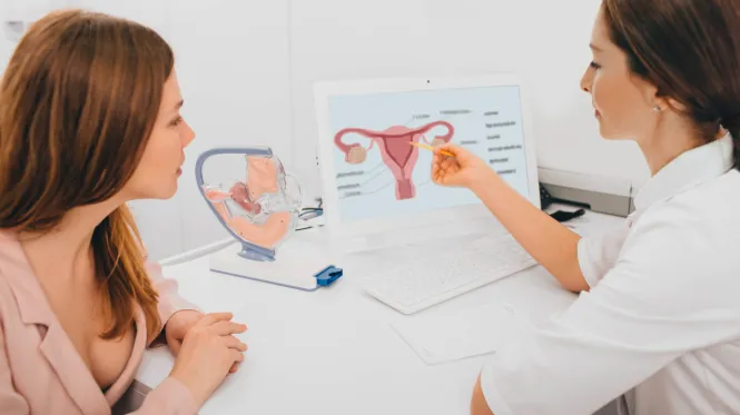 A woman watches as her doctor points to a diagram of a uterus for gynecologic cancer