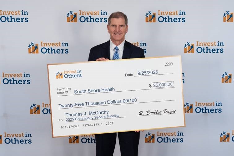 Thomas McCarthy holds an oversized donation check for $25,000 to South Shore Health at the Invest in Others Awards.