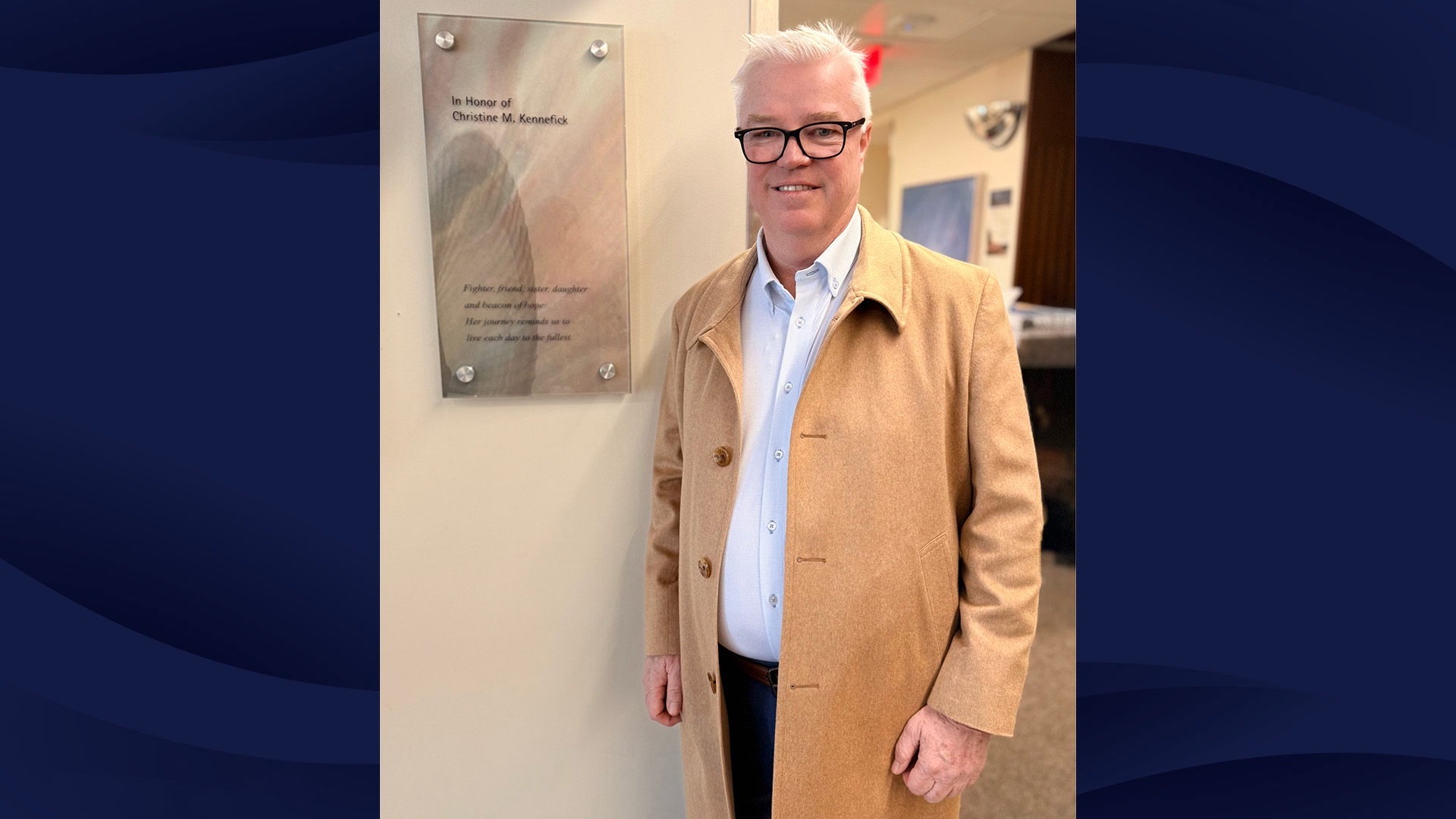 Kevin Kennefick poses with a sign in memory of his sister, Christine