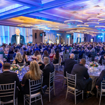 Photo of the full room of attendees seated at the 2025 South Shore Health Gala while Jason Tracy, MD speaks.