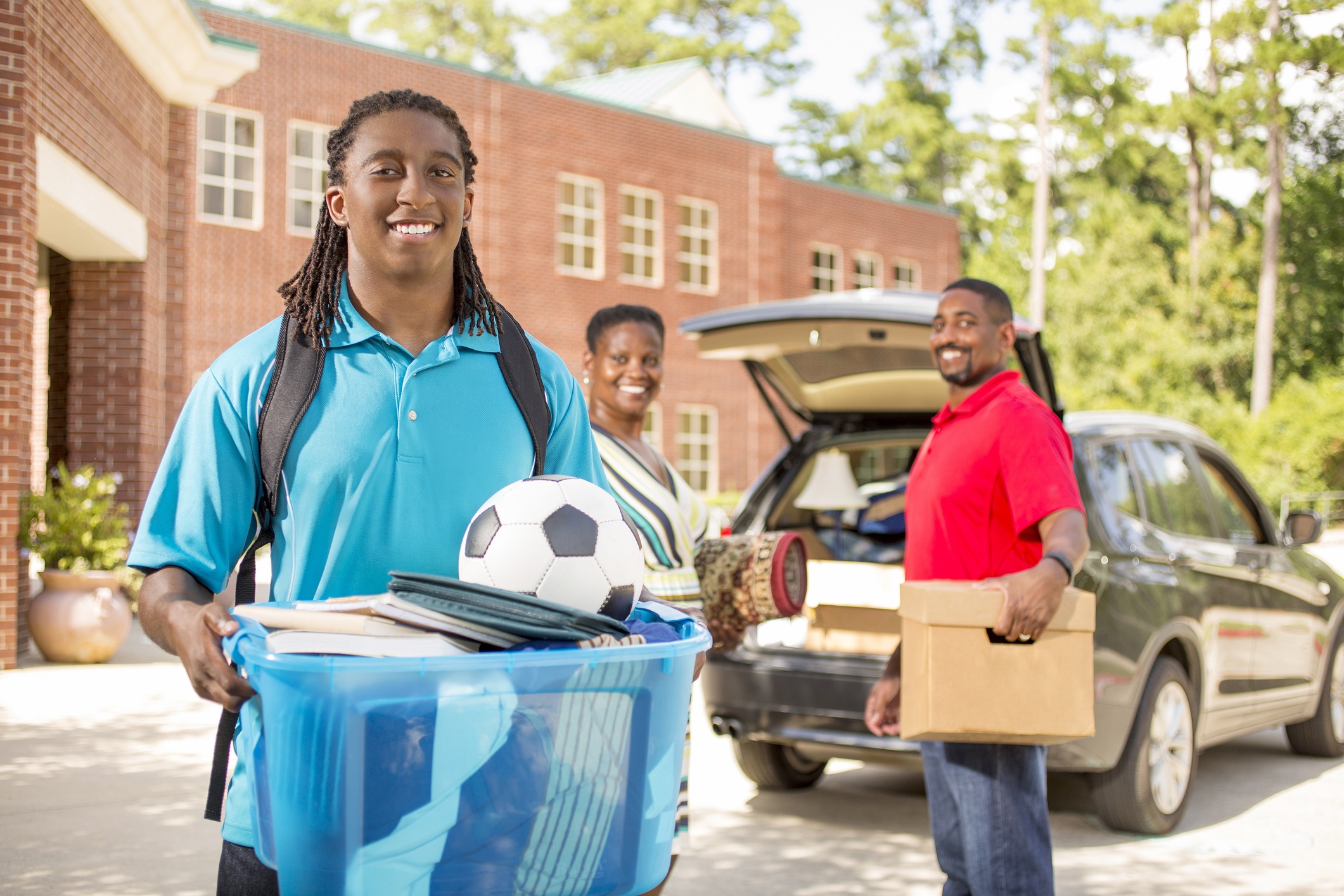 A young black student being dropped off at college by his parents