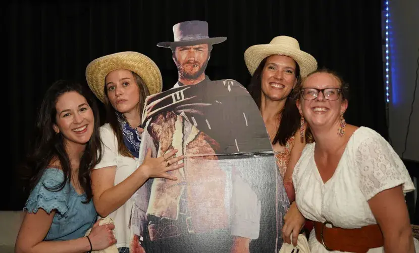 A group of women poses with a cardboard cutout of Clint Eastwood in wester attire