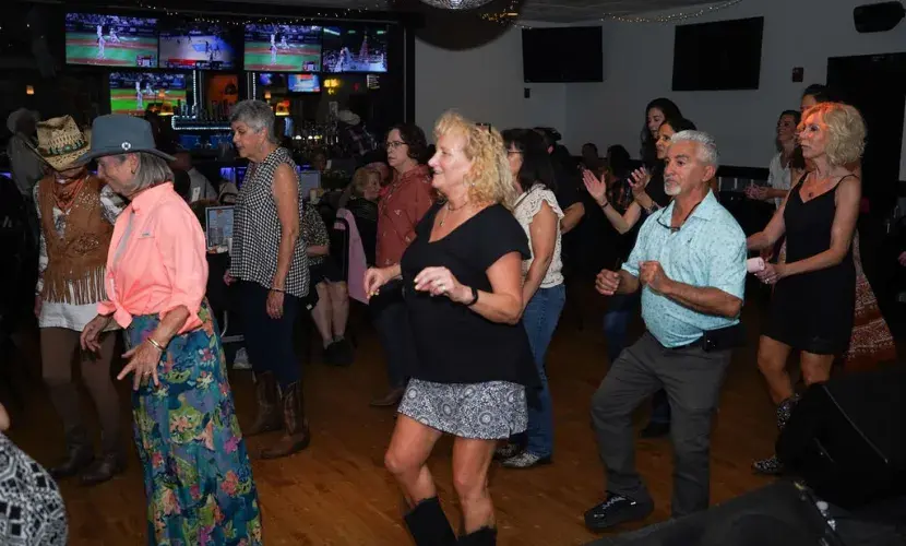 A group of older adults line dances at Kickin' Up Country 2025.