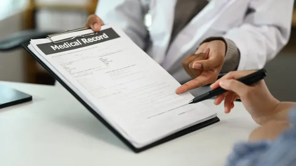 Photo of a doctor holding a clipboard with "Medical Record" papers at the top