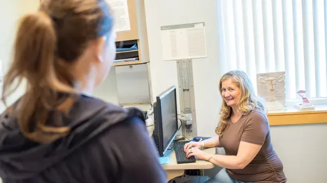 An OB/GYN provider at computer consulting with patient