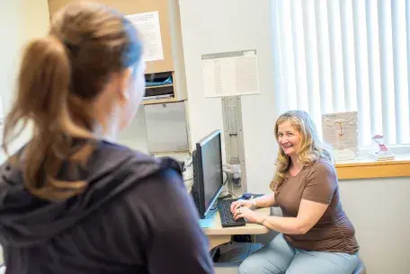 An OB/GYN provider at computer consulting with patient