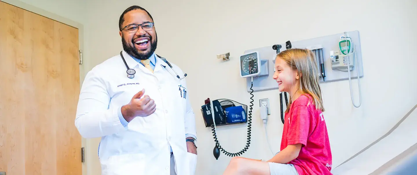 Khalil Alleyne, MD of South Shore Medical Center laughs with a young patient during a visit