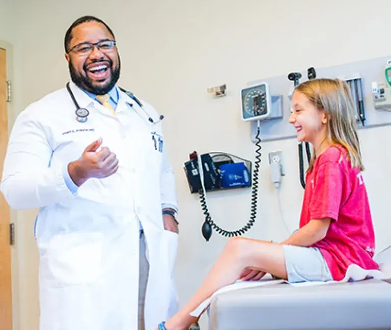 Khalil Alleyne, MD of South Shore Medical Center laughs with a young patient during a visit