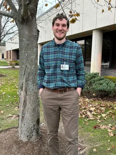 Occupational Therapist Colin O'Donnell stands beside a tree outside South Shore VNA offices