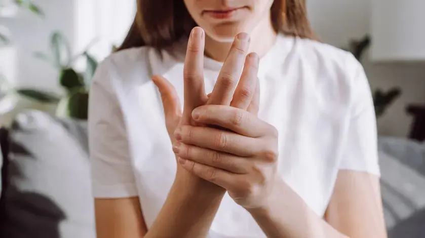 Young woman rubbing her arthritic hand