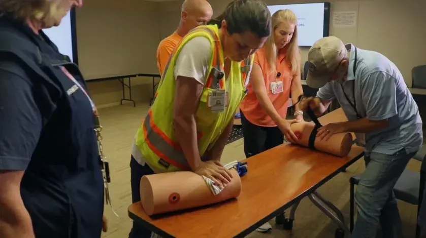 A worker from DPR Construction applies pressure to a prosthetic limb as a South Shore Health colleague looks on during a Stop the Bleed training session.