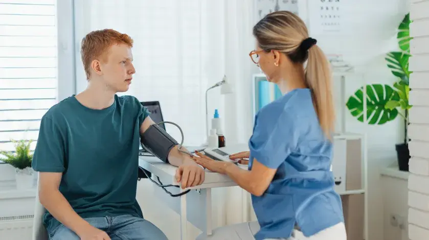 A male student athlete has his blood pressure checked during a sports physical