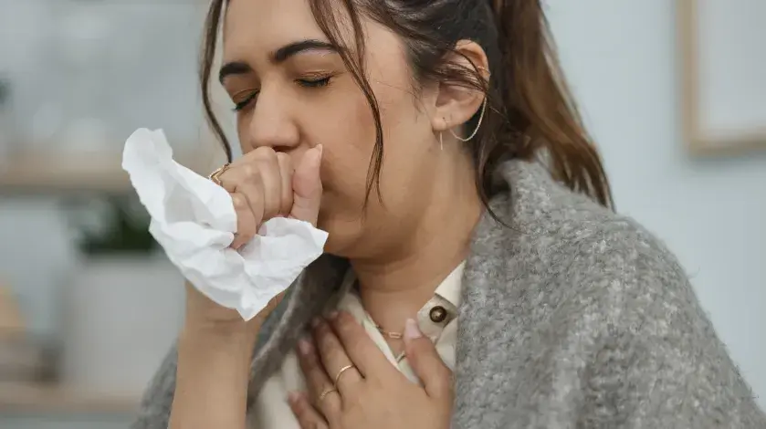 A woman coughs into a tissue