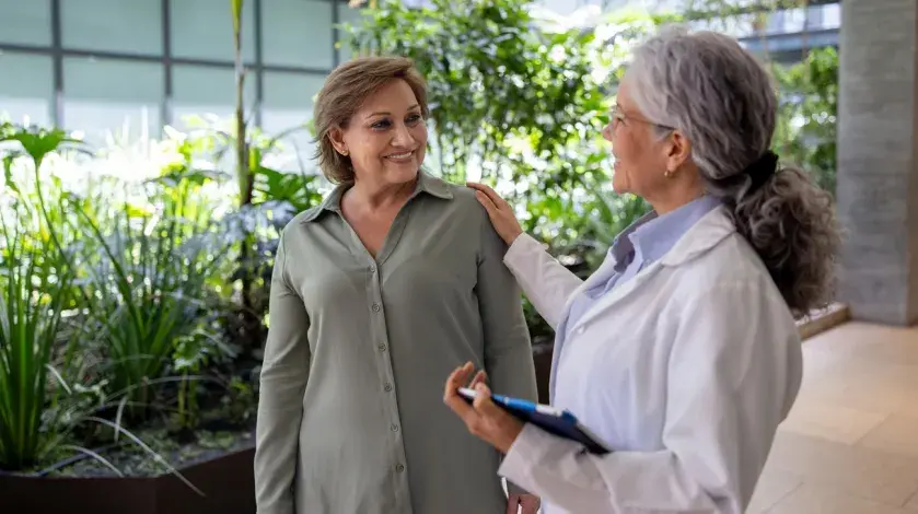 A female provider rests her hand on the shoulder of a middle aged female patient.