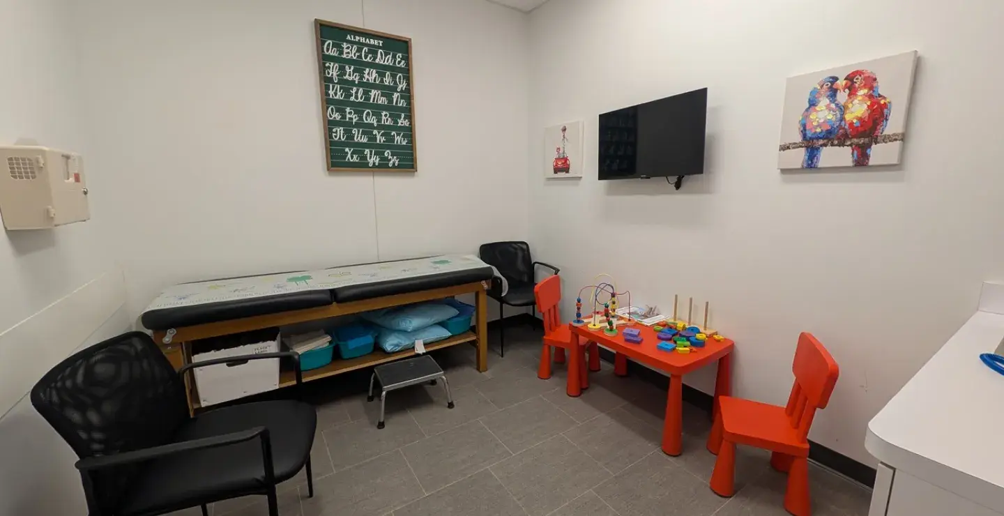 View of a pediatric urgent care room at South Shore Health Urgent Care Braintree, with kid-friendly artwork, toys, chairs, and games.