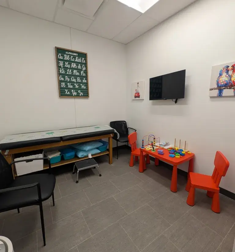 View of a pediatric urgent care room at South Shore Health Urgent Care Braintree, with kid-friendly artwork, toys, chairs, and games.