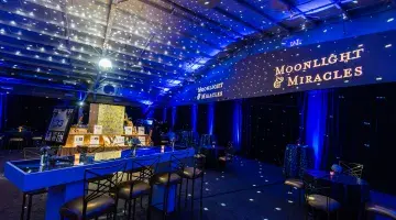 The silent auction and reception space at the 2023 Moonlight & Miracles Gala, featuring elegant displays and blue lightning