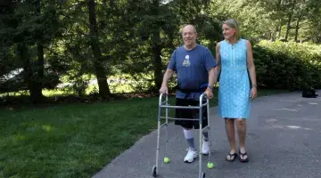 Ed, using a walker, walks next to his wife, Sara, in the driveway of their Duxbury home.