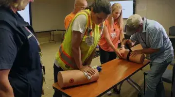 A worker from DPR Construction applies pressure to a prosthetic limb as a South Shore Health colleague looks on during a Stop the Bleed training session.