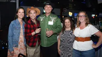 A group of people in cowboy/western attire poses for a photo at Kickin' Up Country 2025.