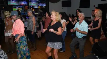 A group of older adults line dances at Kickin' Up Country 2025.